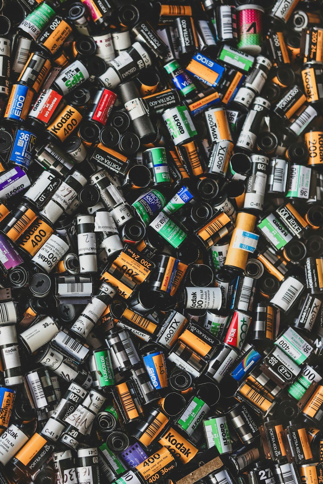 Colorful rolls of 35mm film stock scattered on a table with negative strips