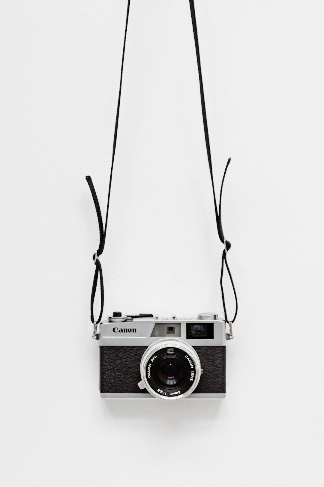 Vintage 35mm film camera resting on a worn wooden desk with light streaming in