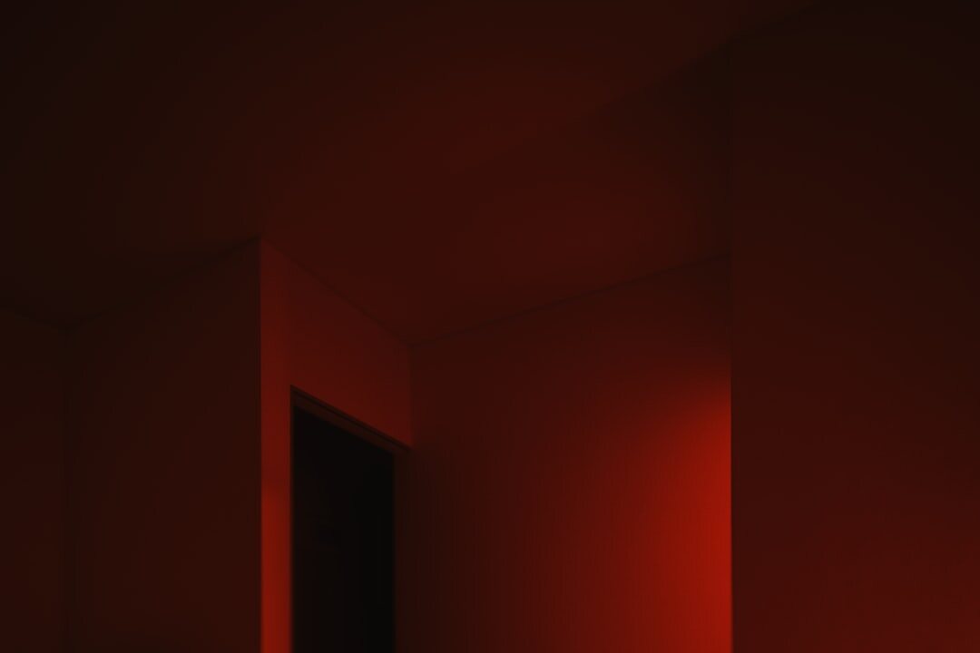 Photographer developing prints under red safelight in an analog darkroom